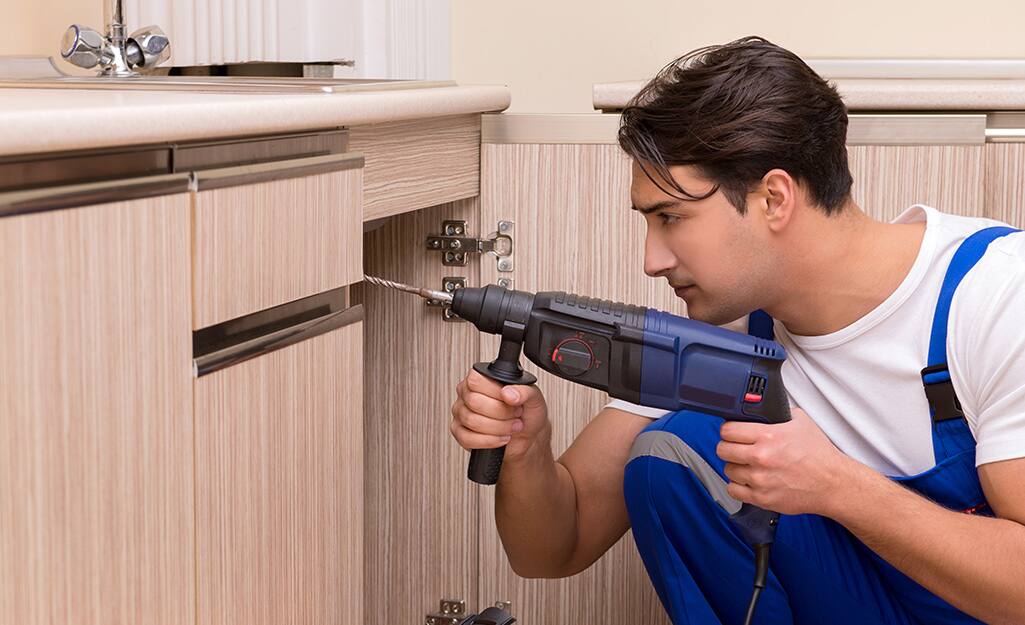 Man uses drill to countersink pilot holes. 