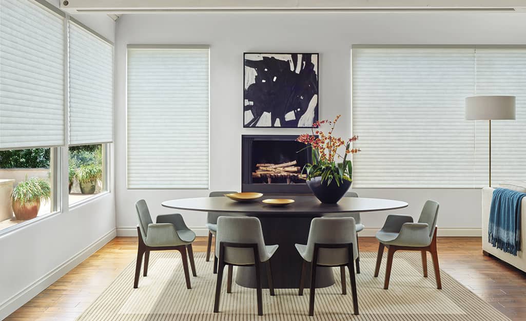 A dining room with windows covered by cellular shades mounted outside the window casings. A dining room with windows covered by cellular shades mounted outside the window casings.