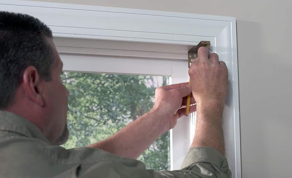 A man installs mounting brackets to hang blinds. A man installs mounting brackets to hang blinds.
