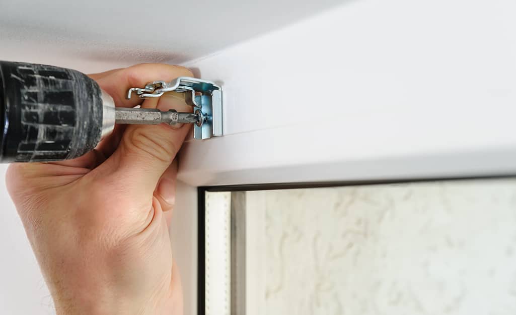 A person uses a drill to install brackets. A person uses a drill to install brackets.