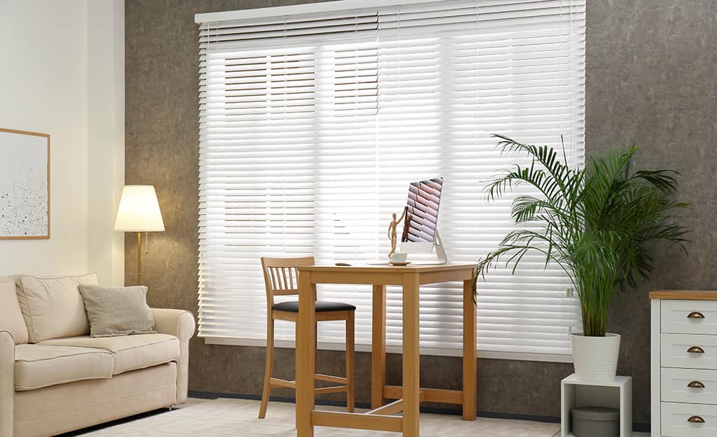 Outside mount horizontal blinds cover the windows in a small living room. Outside mount horizontal blinds cover the windows in a small living room.