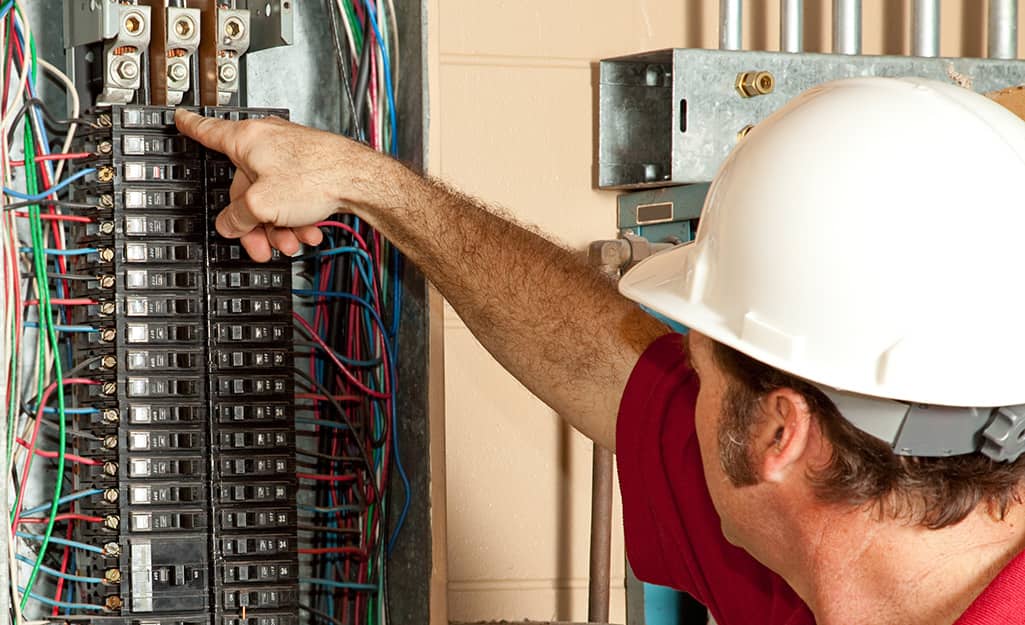 An electrician switching a circuit breaker in an electrical panel. An electrician switching a circuit breaker in an electrical panel.