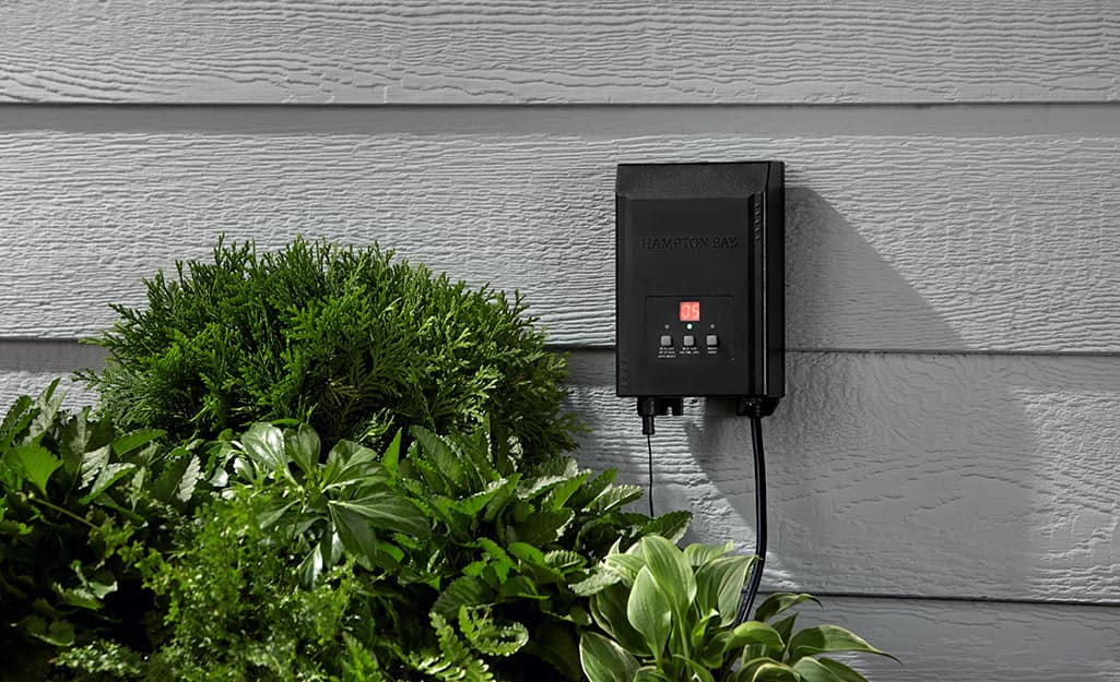 A low voltage landscape lighting transformer mounted to the side of a house. A low voltage landscape lighting transformer mounted to the side of a house.