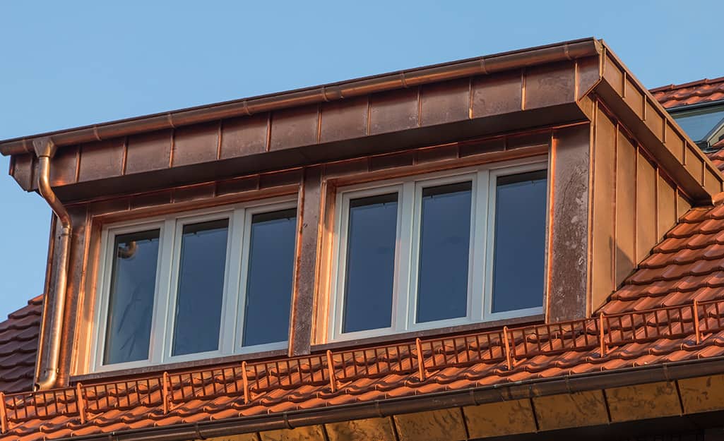 A home features a copper roof and attic windows. A home features a copper roof and attic windows.