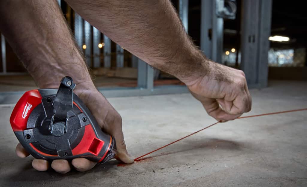 A man snaps a chalk line before installing flooring. A man snaps a chalk line before installing flooring.