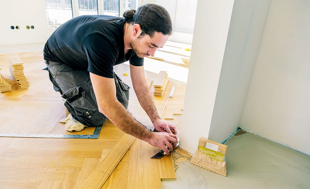 A man cuts the tile to fit the wall. A man cuts the tile to fit the wall.