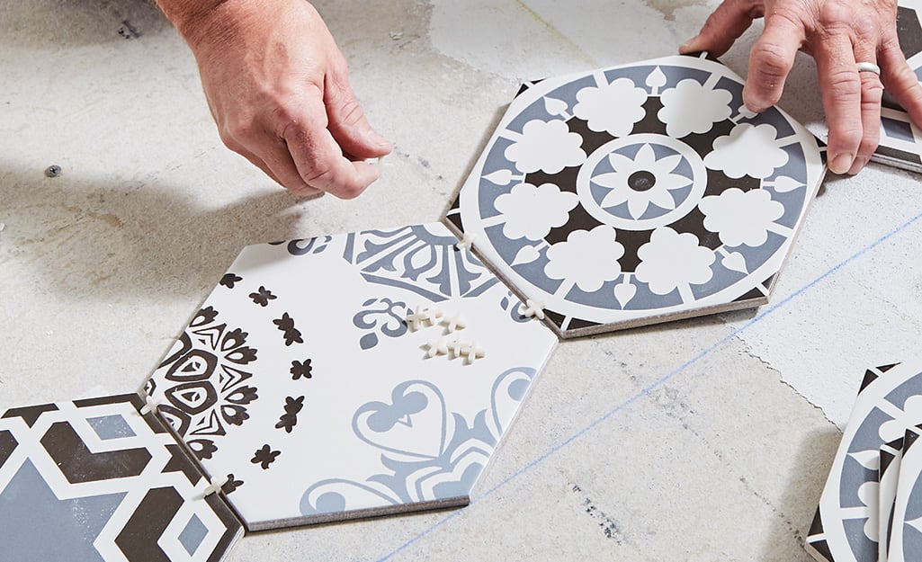 Person putting spacers between blue and white tiles. Person putting spacers between blue and white tiles.