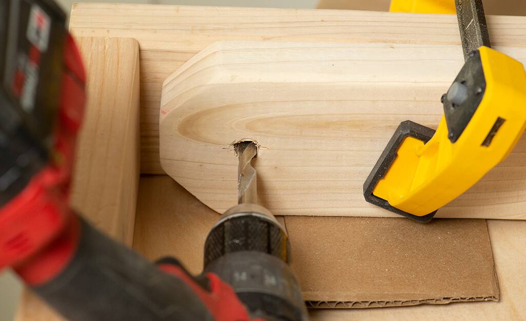 A person attaching a leg of a cornhole board. A person attaching a leg of a cornhole board.