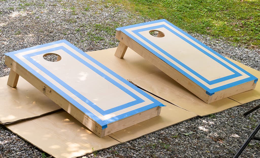 Taped off cornhole boards resting on cardboard waiting to be painted Taped off cornhole boards resting on cardboard waiting to be painted