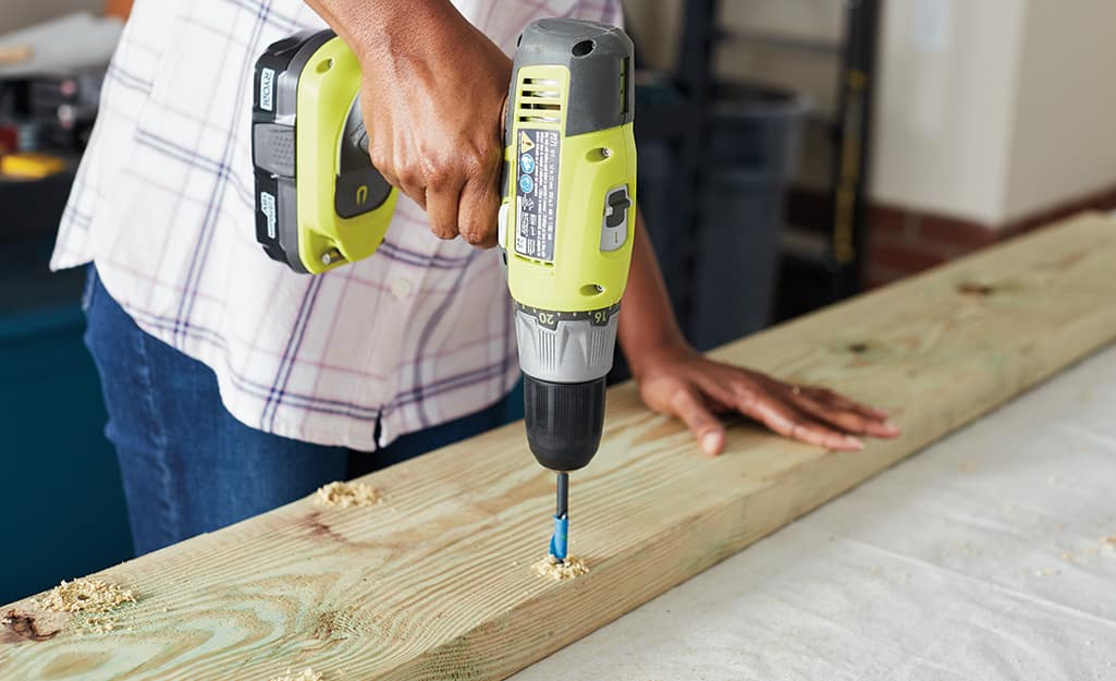 A person drilling a hole in a piece of wood. A person drilling a hole in a piece of wood.