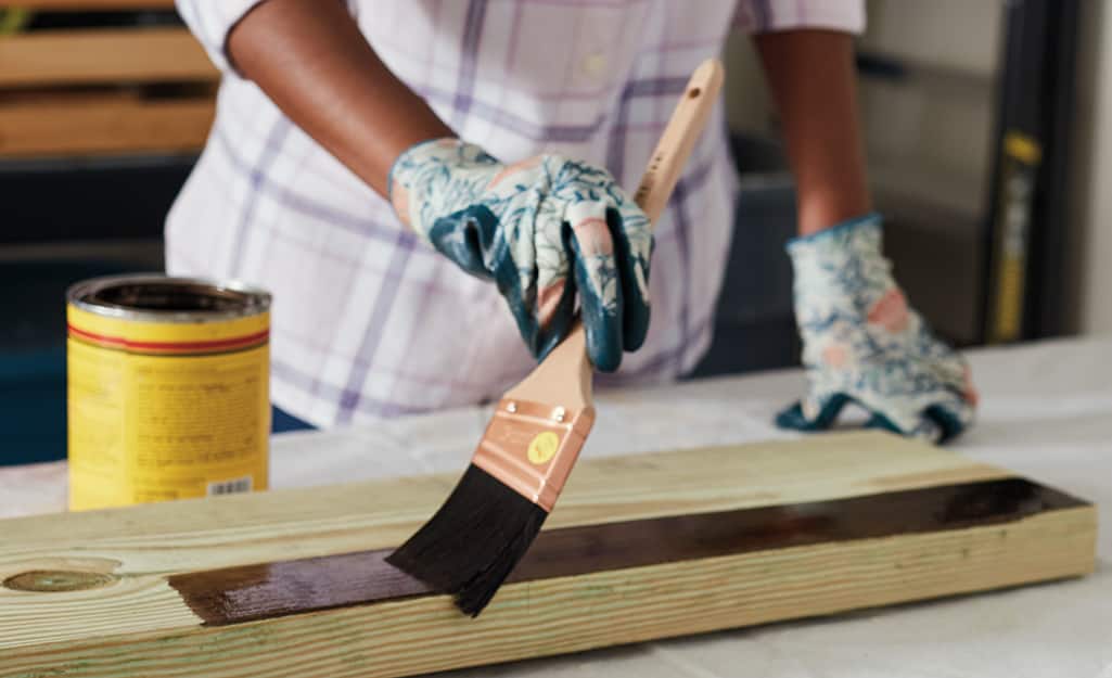 A person applying stain onto a piece of wood. A person applying stain onto a piece of wood.