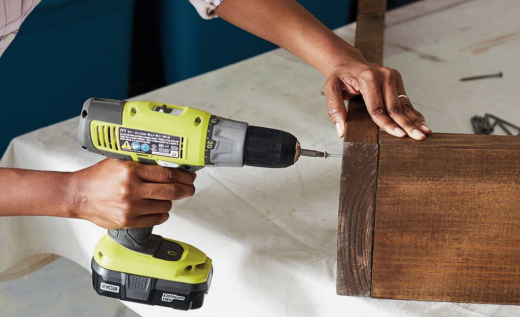 A person driving a screw into a piece of wood. A person driving a screw into a piece of wood.