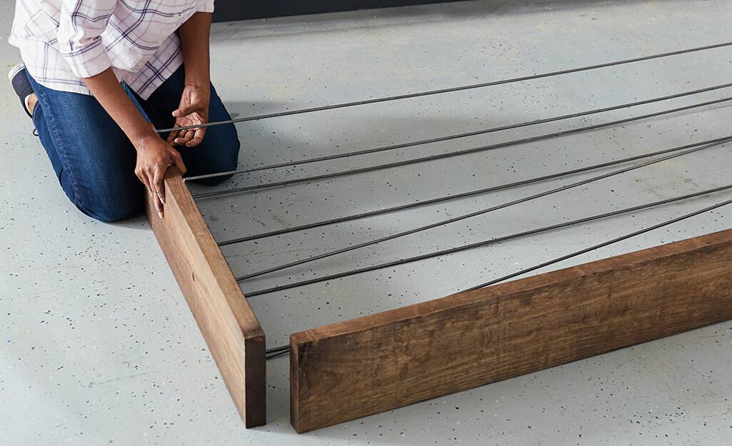 A person attaching metal rebar into a piece of wood. A person attaching metal rebar into a piece of wood.