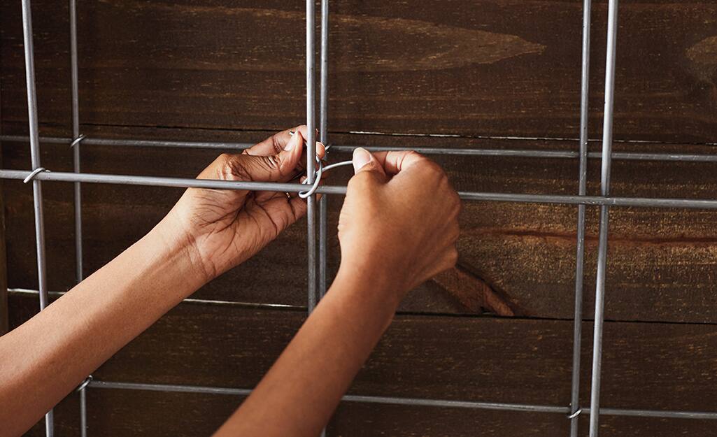 A person tying wire onto metal rebar. A person tying wire onto metal rebar.