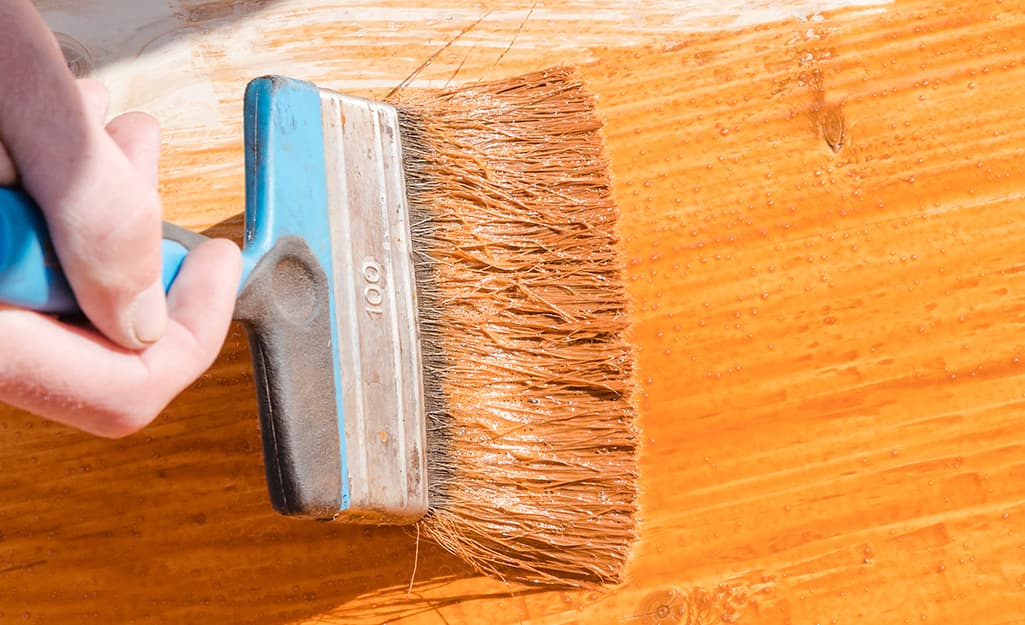 Someone staining a board to make a tree swing. Someone staining a board to make a tree swing.