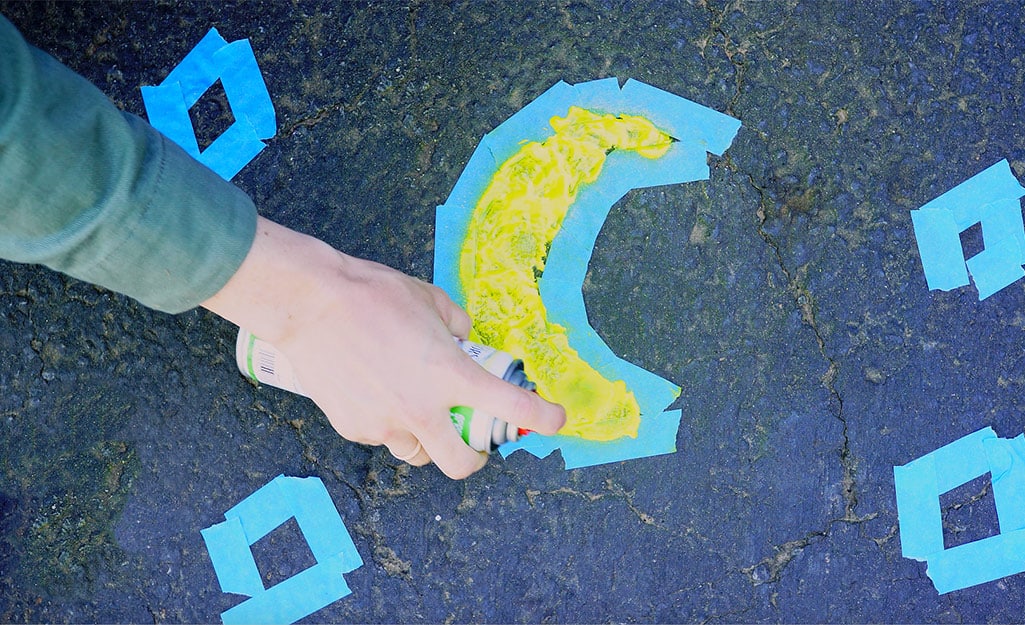 A woman uses a sidewalk chalk spray paint to create art. A woman uses a sidewalk chalk spray paint to create art.