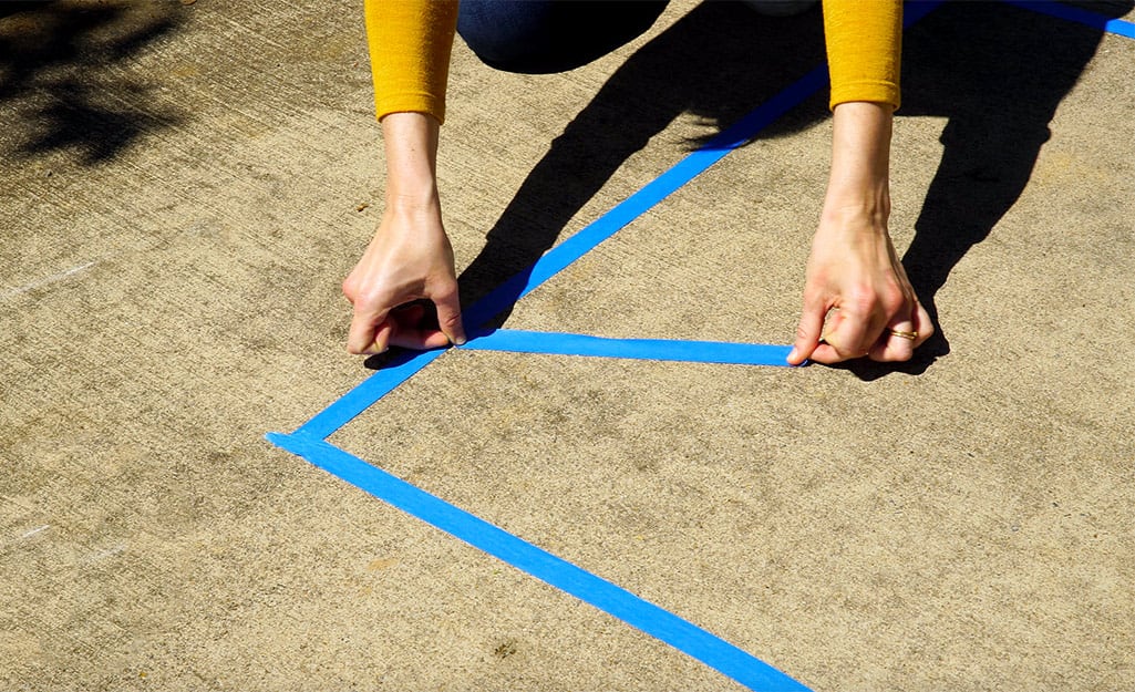 A woman uses painter's tape to outline her design. A woman uses painter's tape to outline her design.