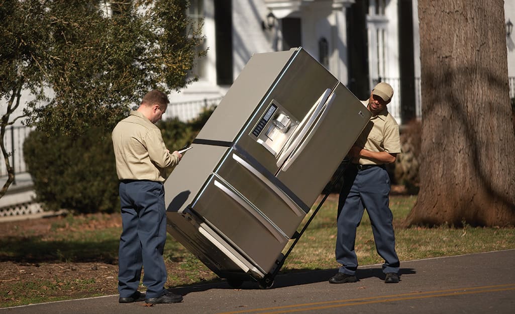 Two people moving a refrigerator. Two people moving a refrigerator.