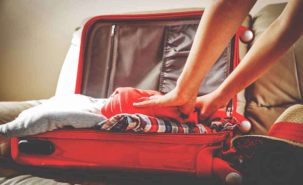 Someone packing a suitcase with clothes. Someone packing a suitcase with clothes.
