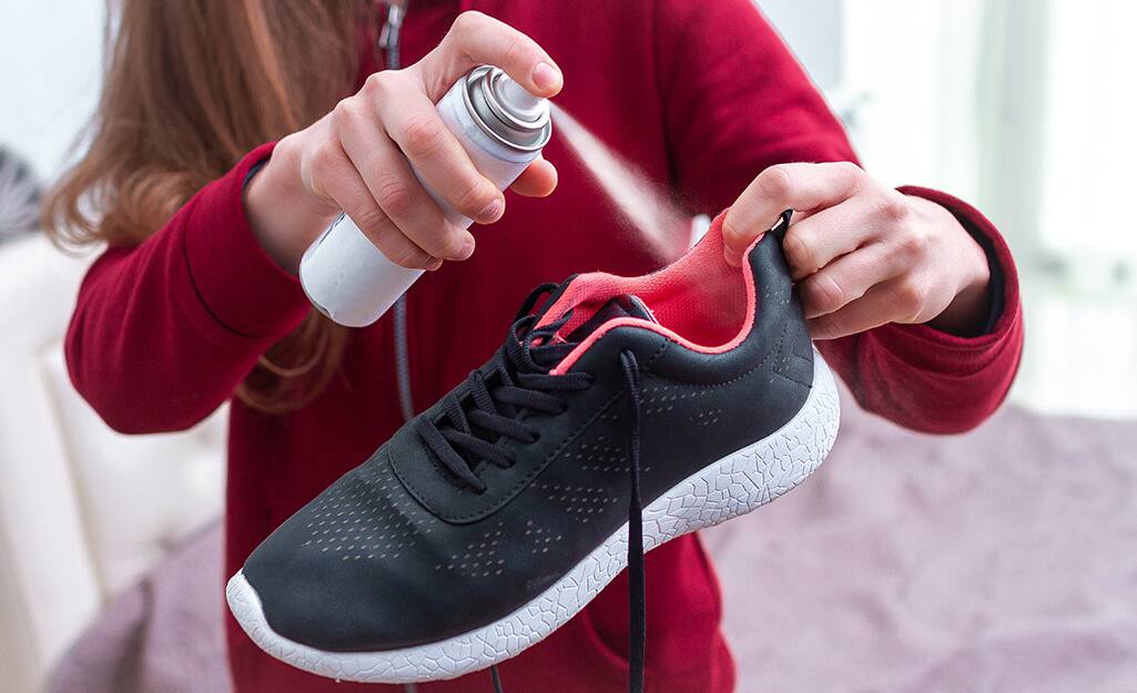 Someone spraying a sneaker with deodorizing spray. Someone spraying a sneaker with deodorizing spray.
