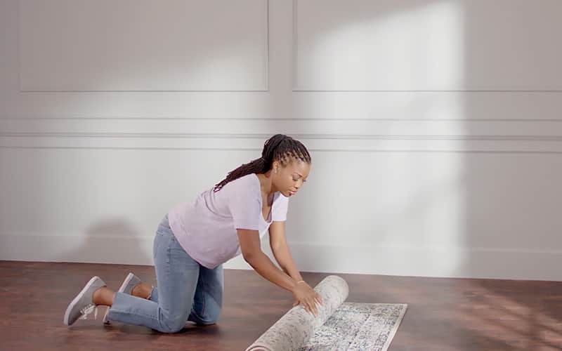 Woman removing rugs in preparation for painting. Woman removing rugs in preparation for painting.
