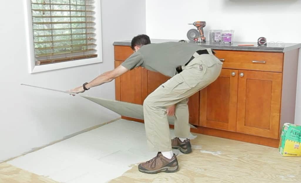 A person placing a sheet of backerboard on a wood subfloor. A person placing a sheet of backerboard on a wood subfloor.