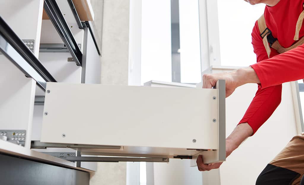 A person removes a kitchen cabinet drawer. A person removes a kitchen cabinet drawer.
