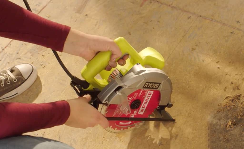 Someone using a circular saw on a wood subfloor. Someone using a circular saw on a wood subfloor.