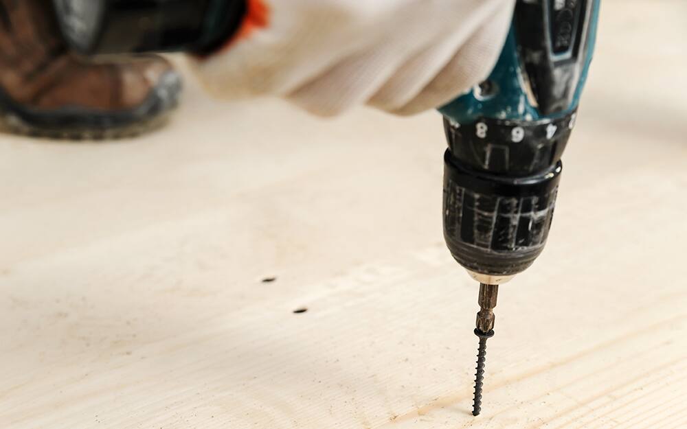 person using a power drill on laminate flooring