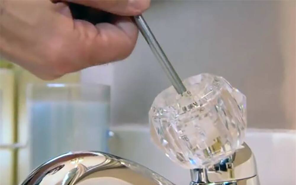 A screw is loosened to remove the handle from a ball faucet. A screw is loosened to remove the handle from a ball faucet.
