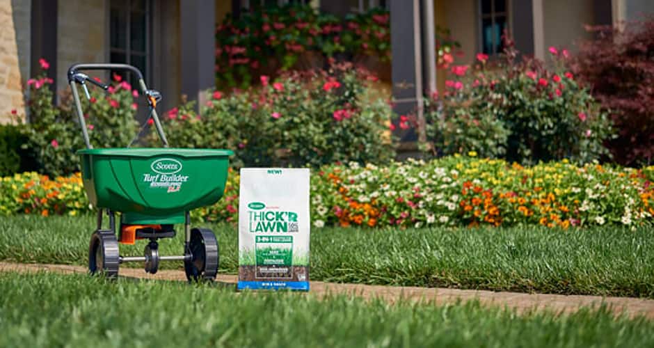A spreader and bag of fertilizer in a garden A spreader and bag of fertilizer in a garden