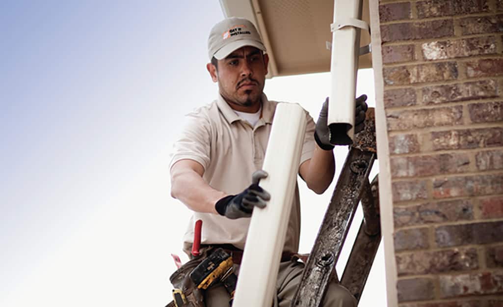 A man inspecting a removed section of downspout. A man inspecting a removed section of downspout.