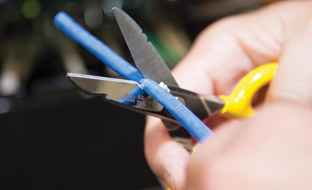 Someone cutting an unplugged electrical cord with shears. Someone cutting an unplugged electrical cord with shears.