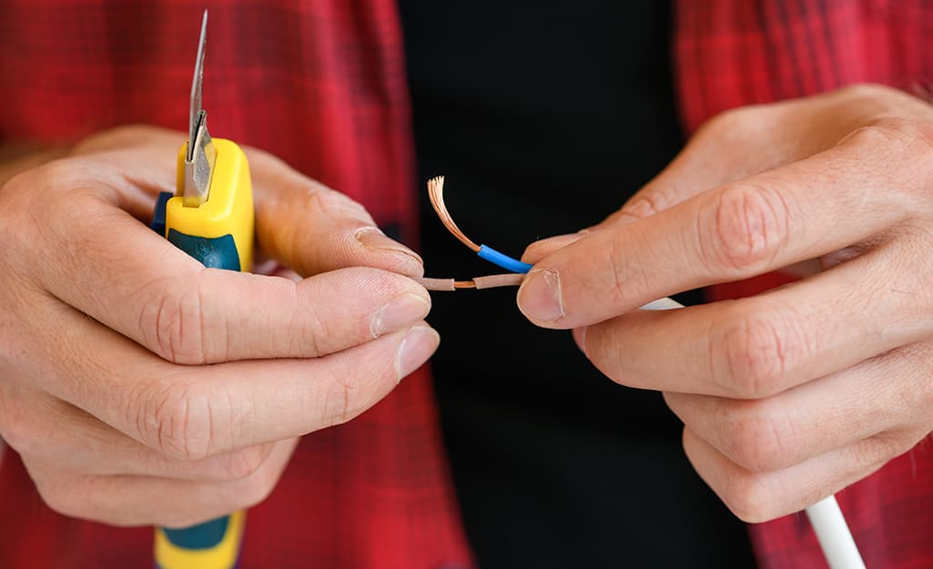 Someone stripping insulation off split Y-shaped wires. Someone stripping insulation off split Y-shaped wires.