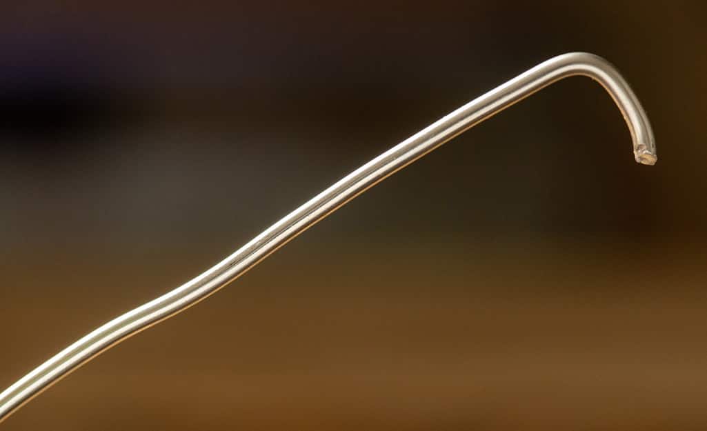 A piece of solder with the end bent at a 90-degree angle. A piece of solder with the end bent at a 90-degree angle.