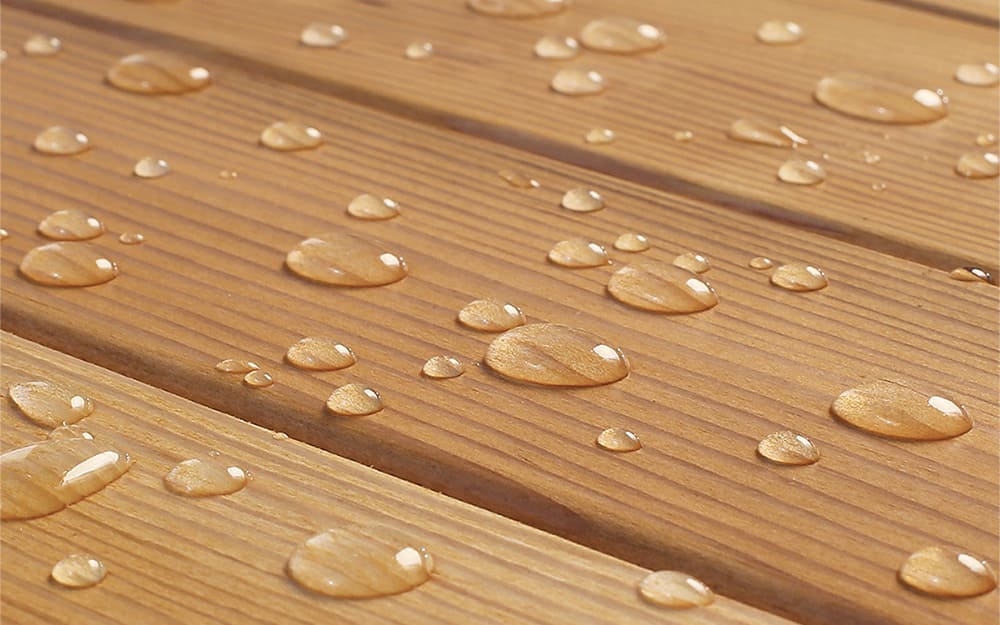 Water droplets bead on a pressure-treated wood surface. Water droplets bead on a pressure-treated wood surface.