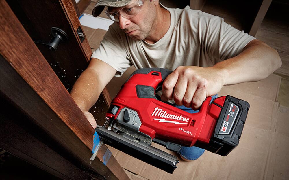 A person using a jigsaw to cut wood. A person using a jigsaw to cut wood.
