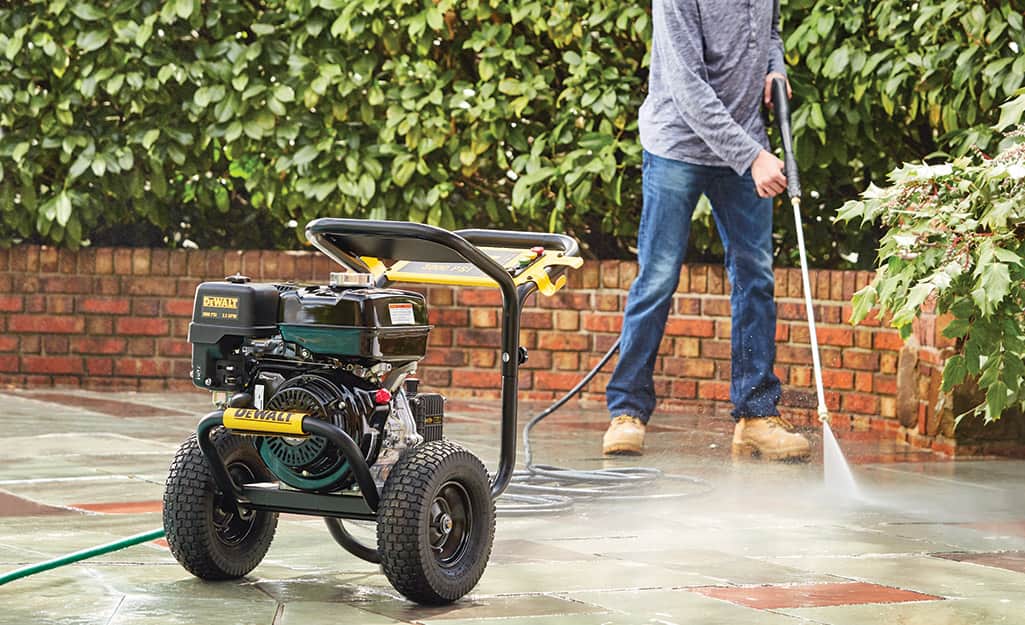 A man pressure washes his sidewalk. A man pressure washes his sidewalk.