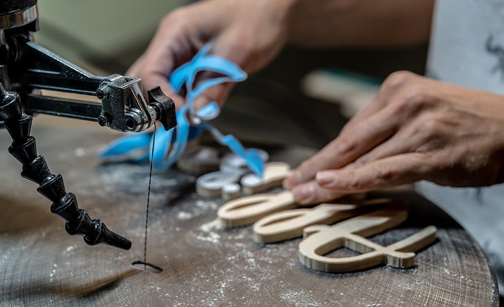 A person dusting off a workpiece on a scroll saw table. A person dusting off a workpiece on a scroll saw table.