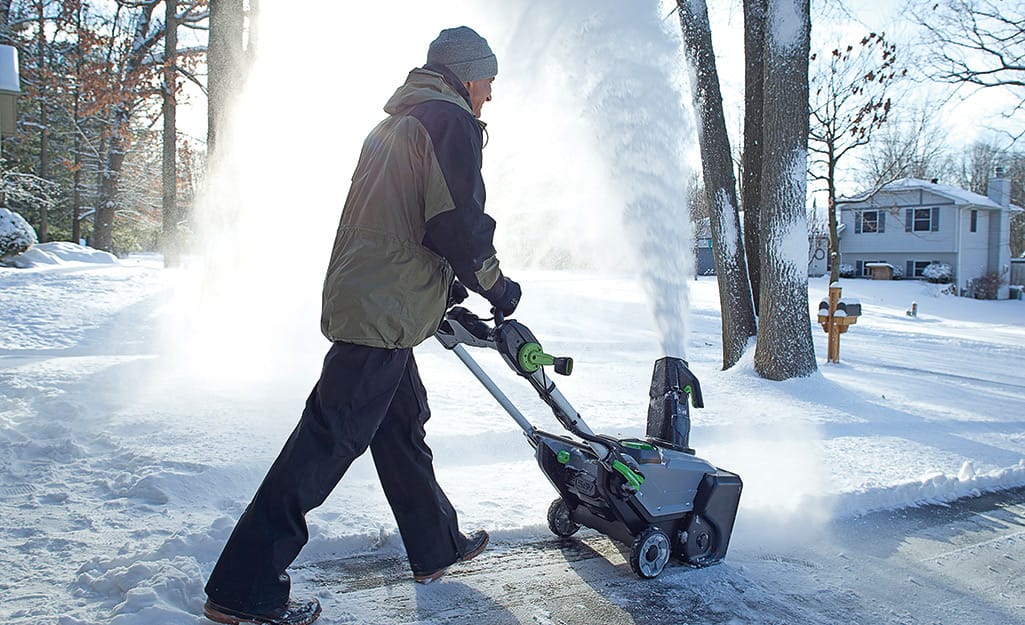 Person using a snow blower to remove snow. Person using a snow blower to remove snow.