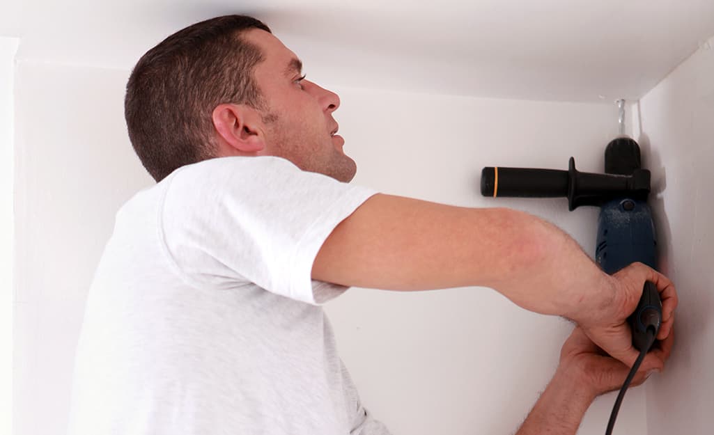 A man drilling a hole into the wall. A man drilling a hole into the wall.