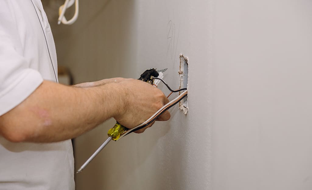 A man trying to move a wire past a fire block in a wall. A man trying to move a wire past a fire block in a wall.