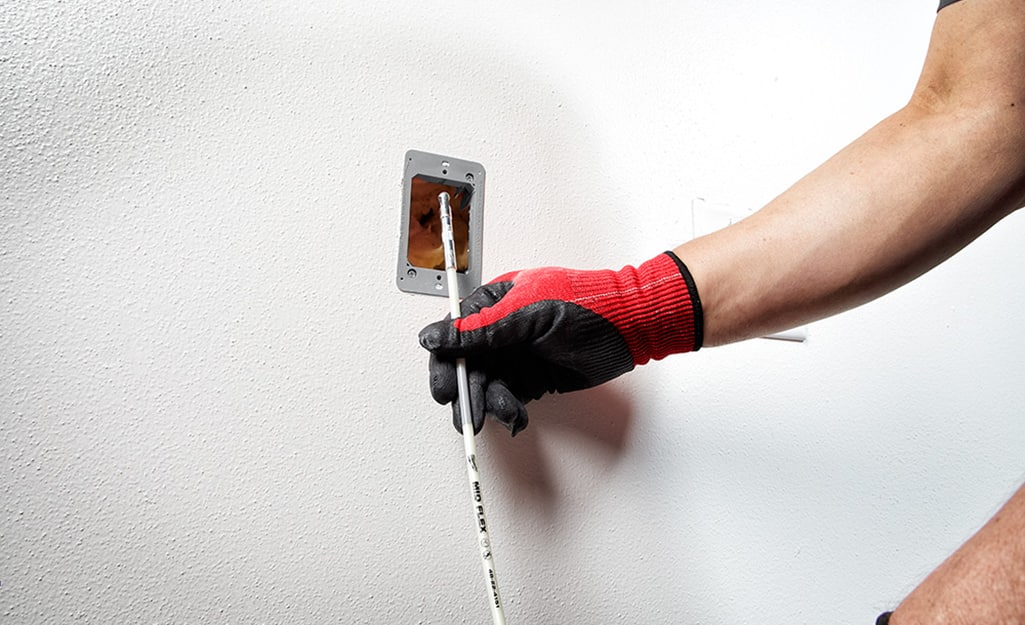 A person pulling the cable through the wall. A person pulling the cable through the wall.