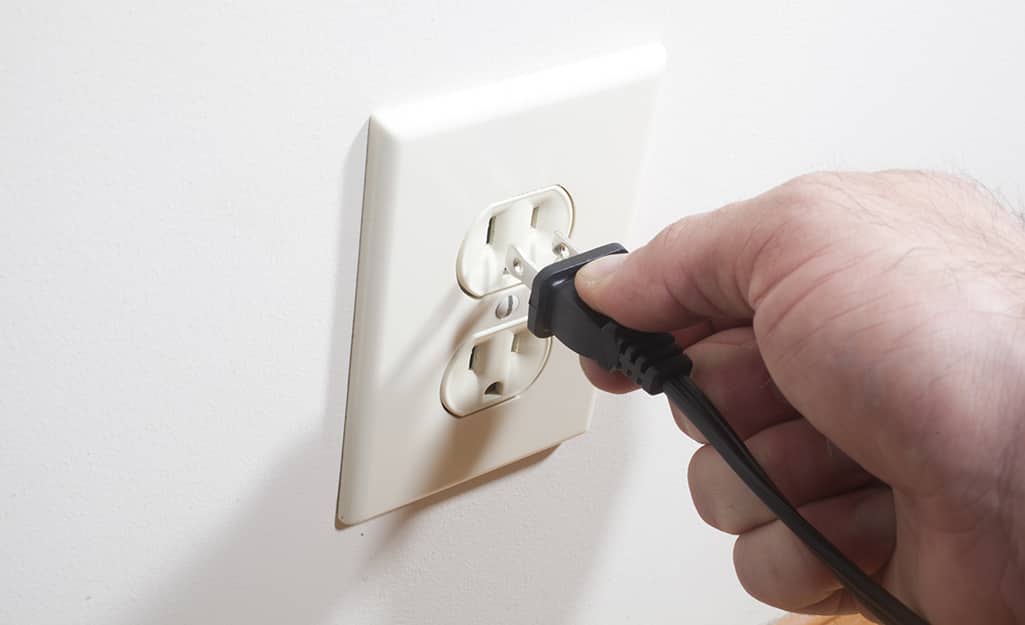 A person plugging a cord into an outlet. A person plugging a cord into an outlet.