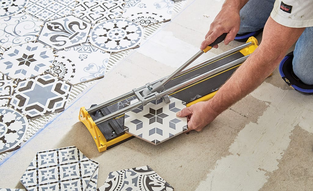 Man cutting tile with a manual tile cutter. Man cutting tile with a manual tile cutter.