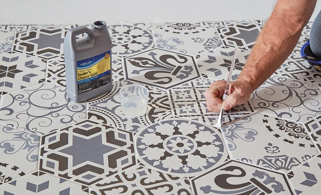 Person sealing grout using a small brush. Person sealing grout using a small brush.