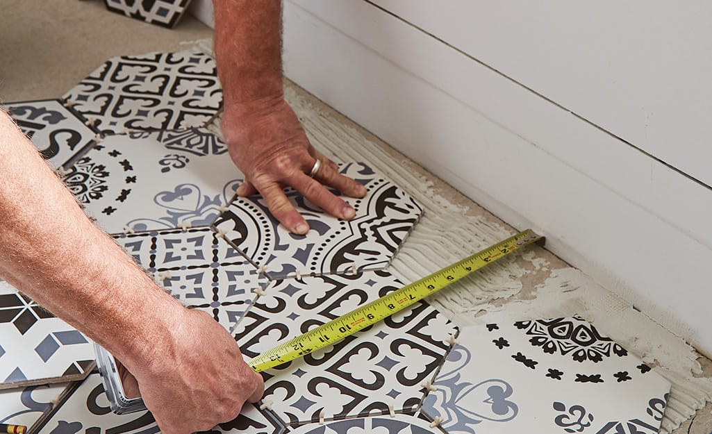 Someone measuring tile and floor. Someone measuring tile and floor.