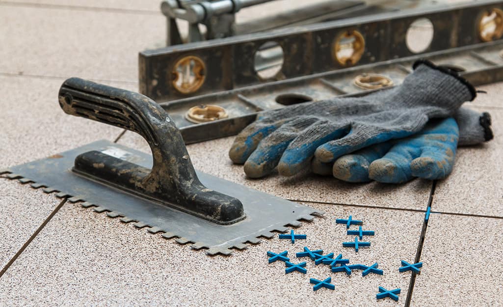 A trowel, spacers and level placed next to work gloves. A trowel, spacers and level placed next to work gloves.