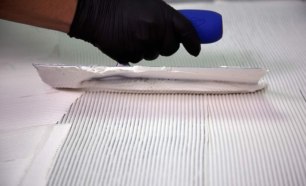 Person applying grout or thin-set with a trowel. Person applying grout or thin-set with a trowel.