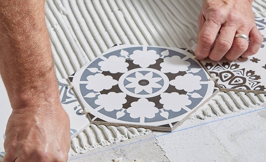 Man adding spacers between round tiles. Man adding spacers between round tiles.